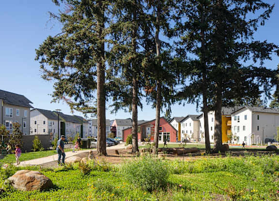 A row of houses with trees in front of them.