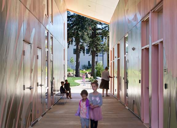 A long hallway with pink walls and a girl walking down it.