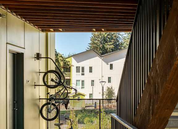 A bicycle is leaning against a wall on a wooden deck.