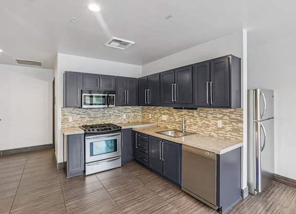 A kitchen with a stove, sink, and refrigerator.