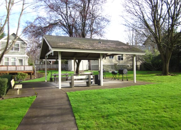 a pavilion with a sidewalk and picnic table in a yard
