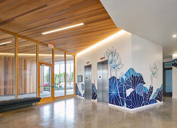 A hallway with a mural of blue leaves on the wall.
