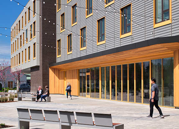 A modern building with a wooden facade and a person walking in front.