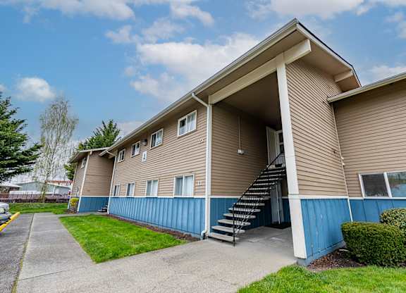 A beige and blue apartment building with a staircase leading to the entrance.