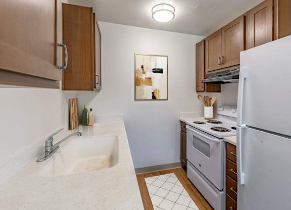 A small kitchen with a white refrigerator, white sink, and a white stove.