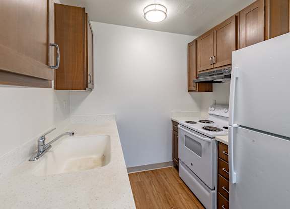 A kitchen with a sink, stove, and refrigerator.