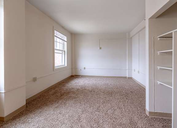 A large, empty room with a carpeted floor and a window.