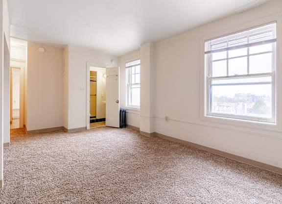 A large empty room with a carpeted floor and a window.