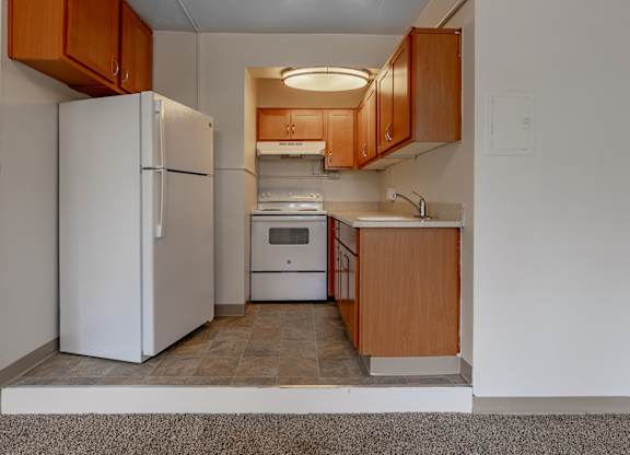 A kitchen with a white refrigerator and wooden cabinets.