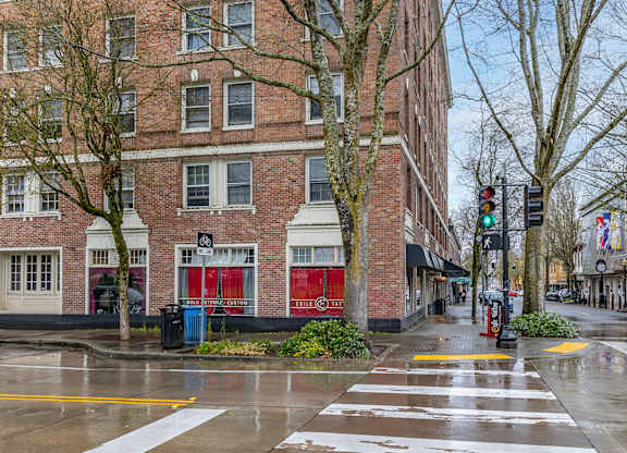 A crosswalk in front of a brick building with a red awning.