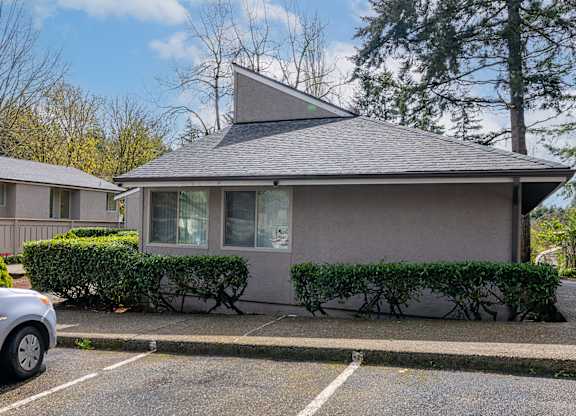 A grey house with a grey roof and a grey car parked in front.