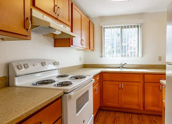 A kitchen with wooden cabinets and a white stove top oven.