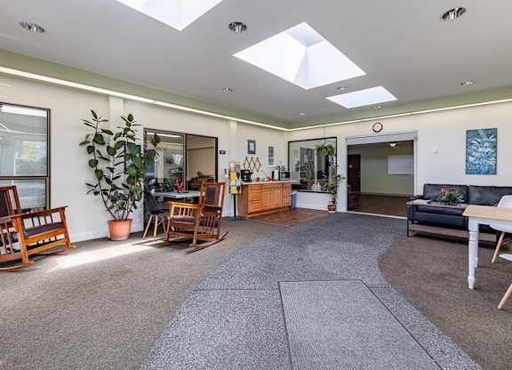 A spacious living room with a grey carpet and wooden furniture.