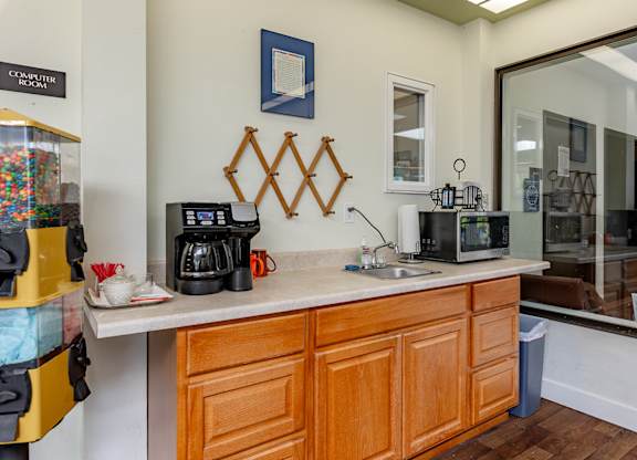 A kitchen with wooden cabinets and a counter with a coffee maker and a microwave.