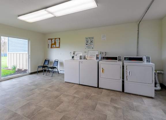 A room with a white fridge, a white washing machine, a white dishwasher, and a white dryer.