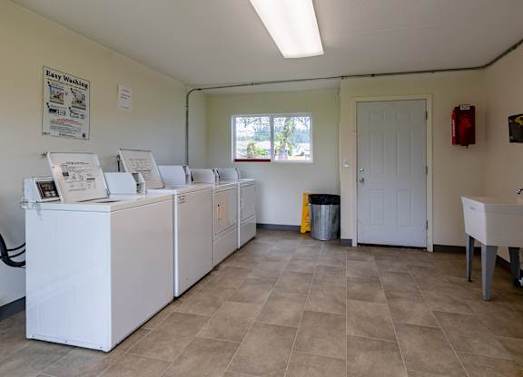 A laundromat with washers and dryers is empty except for one person.