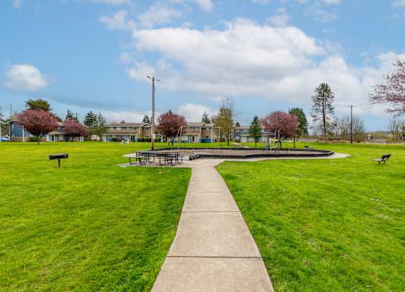 A park with a concrete walkway and green grass.