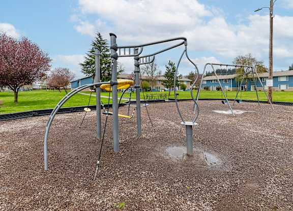 A playground with a swing set and a tree in the background.
