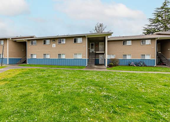 A row of apartment buildings with green grass in front.