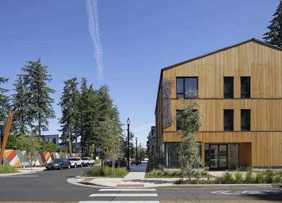 a city street with a yellow building on the left and trees on the right