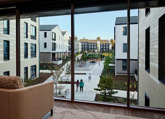 A view from a window of a courtyard with people skating.