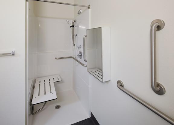 A white shower stall with a bench and grab bars.