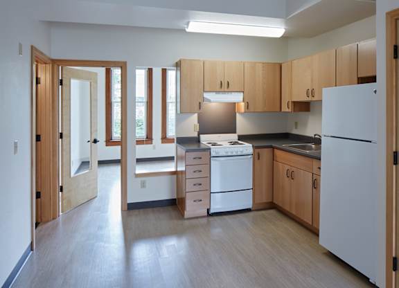 A kitchen with white appliances and wooden cabinets.