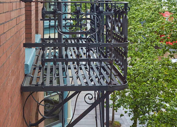 A balcony with a metal railing and a brick wall.