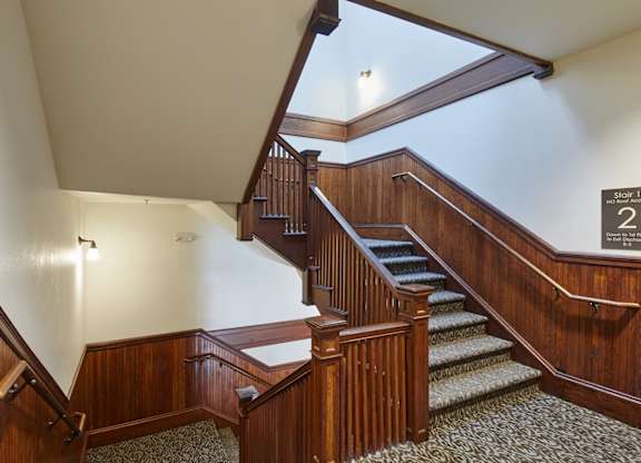 A wooden staircase with a carpeted runner and a wooden handrail.