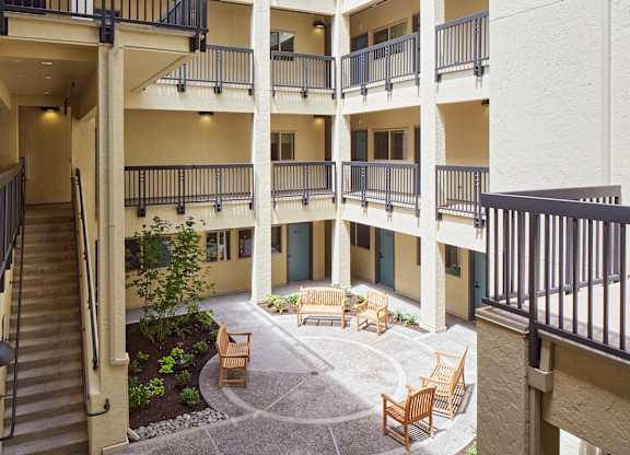 A courtyard with a bench and a tree in the middle of it.