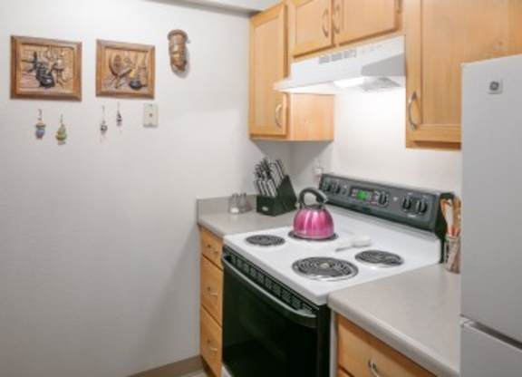 A kitchen with a white stove top oven and a white refrigerator.