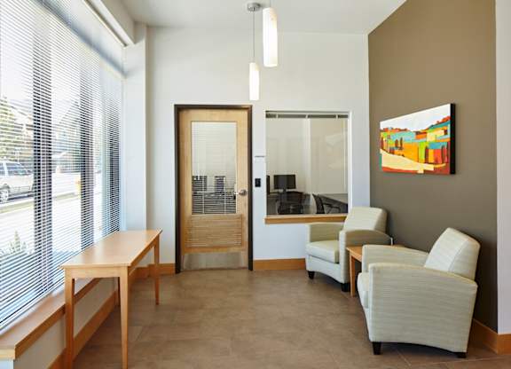 A room with a table, chairs and a painting on the wall.