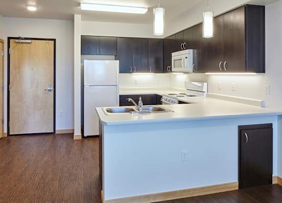 A kitchen with a white counter top and black cabinets.