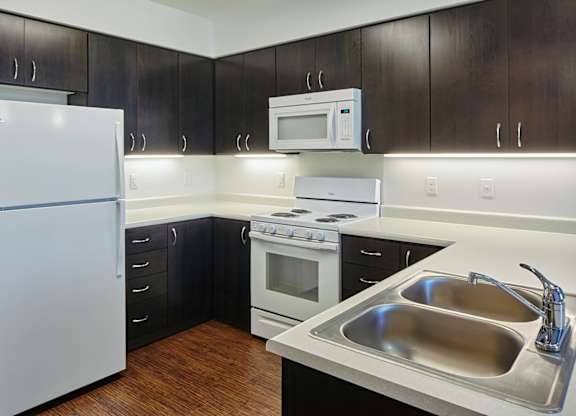 A kitchen with a white refrigerator, a stove, a microwave, and a sink.
