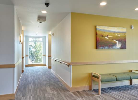 A hallway with a bench and a painting on the wall.