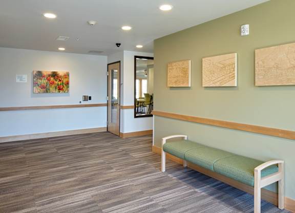 A hallway with a bench and three paintings on the wall.