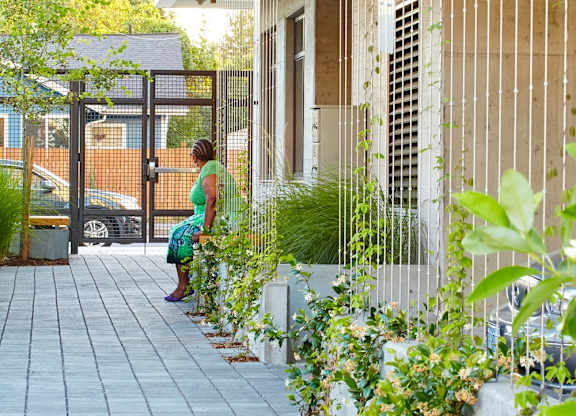 A woman is walking down a sidewalk lined with plants.
