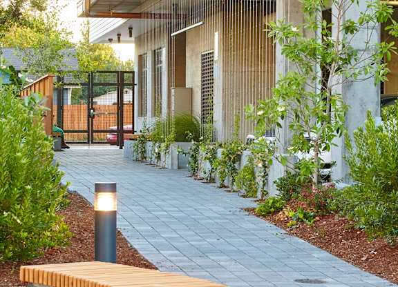 A wooden bench with a metal frame is on a paved walkway.