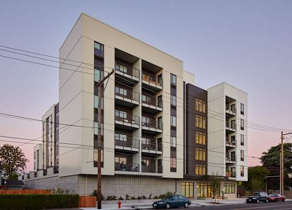 A modern apartment building with cars parked in front.