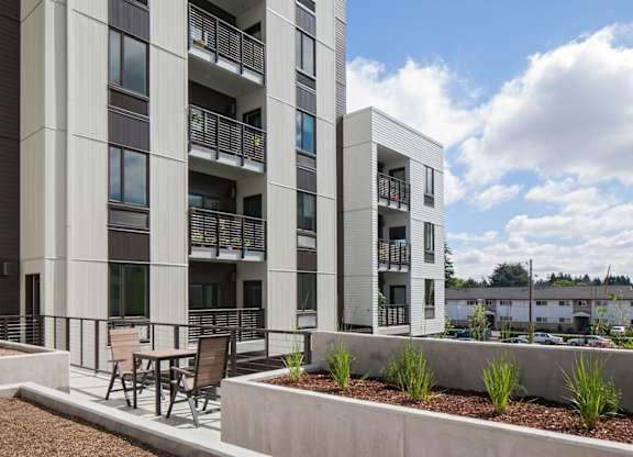A modern apartment building with a balcony and a small garden area.