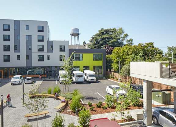 A parking lot with cars and a green building in the background.