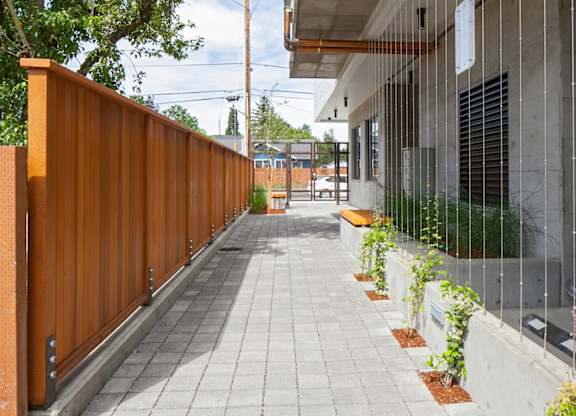 A long concrete walkway with a wooden fence on the left side.