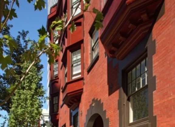 A red brick building with a tree in front.