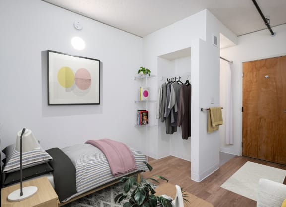 a bedroom with a bed and a closet with clothes hanging on the wall