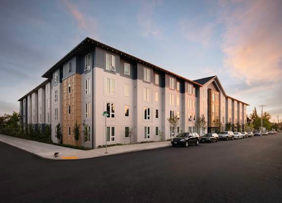 A modern apartment building with a parking lot in front.