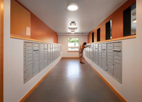 A woman walks down a hallway with lockers on both sides.