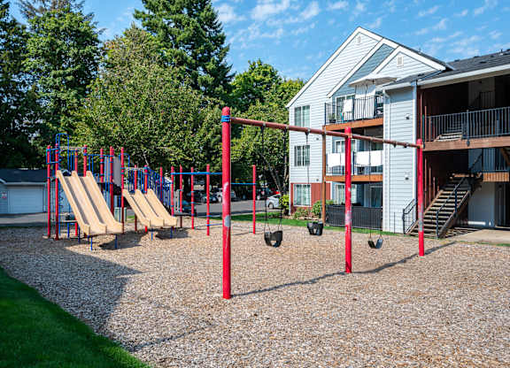 A playground with a red swing set and a slide.