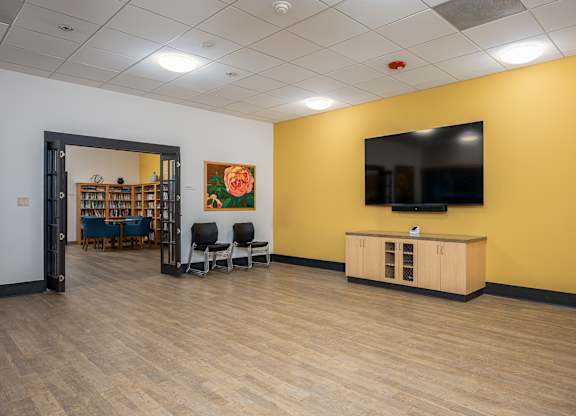 A room with a yellow wall and a television on the wall.