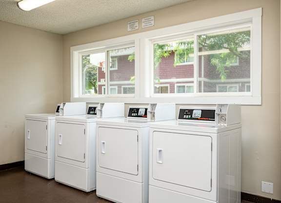 A row of white washing machines in a laundromat.