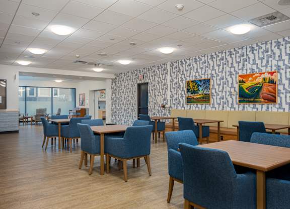 A room with tables and chairs and a wallpapered wall.